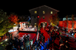 Panoramica notturna dell’area esterna Ariostea con illuminazione rossa e ospiti nel 2019