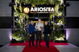 Gruppo di ospiti al portale Ariostea con pareti verdi e tappeto rosso nel 2019