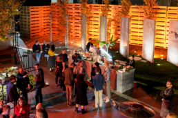 Ospiti nell’area buffet con parete illuminata arancione al Gala Dinner Ariostea 2019