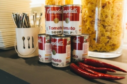 Composizione decorativa con lattine di zuppa sul tavolo del Gala Dinner Iris Ceramica 2017
